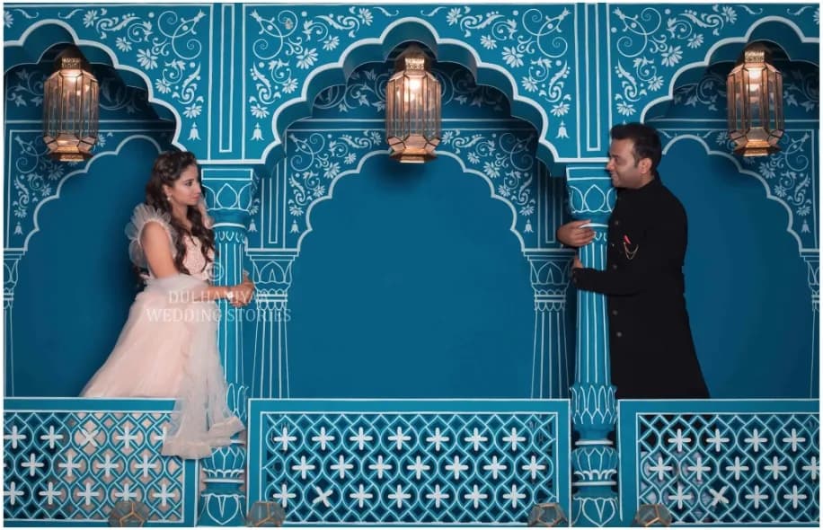 Couple facing each other across carved blue arches lit by lanterns