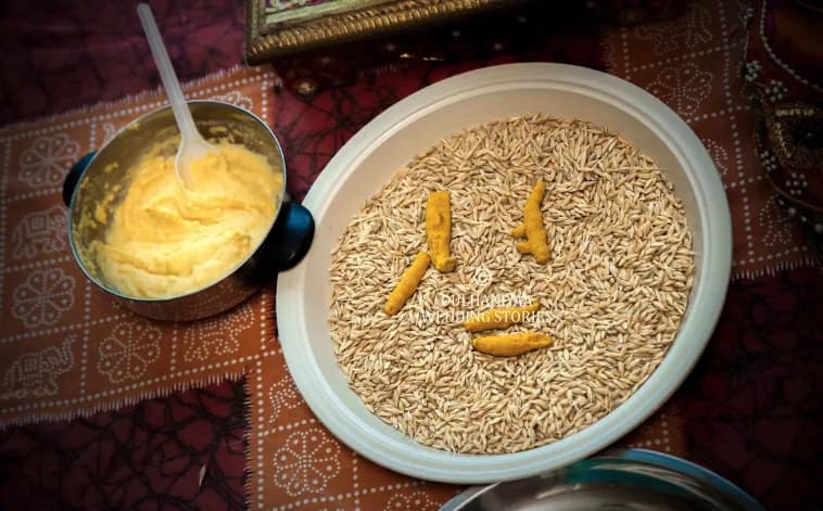 Bowl of fresh haldi paste beside a plate of rice and turmeric for the ceremony